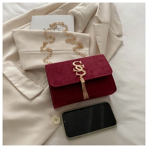 Detail of burgundy velvet crossbody bag with gold chain strap and metallic tassel