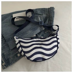 Macro shot of blue and white wave stripes on a crescent crossbody bag with adjustable strap