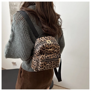Detail shot of leopard print backpack with gold hardware worn over grey knit sweater