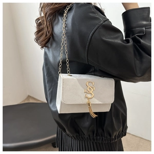 Close-up of minimalist square crossbody bag with gold SS logo and tassel detail