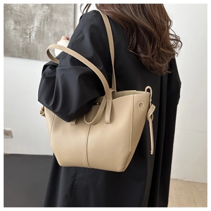 Detail of light beige tote bag with litchi texture and decorative side knots on the strap