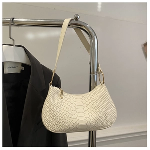 Close-up detail of white snake-patterned texture and pale gold zipper on the shoulder bag