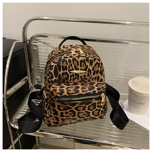 Detail of leopard print backpack with gold hardware and woven black nylon straps