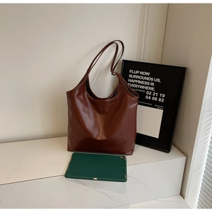 Detailed view of brown large tote bag with soft PU leather texture and laptop for scale