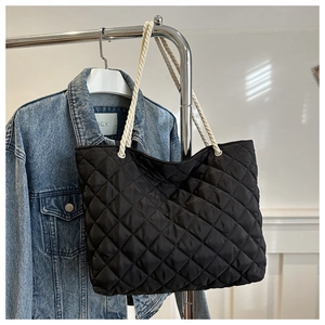 Dettaglio della borsa tote in nylon trapuntato nero con manici in corda bianca appesa