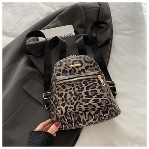 Detail of leopard print mini backpack with golden zipper on a gray suit background