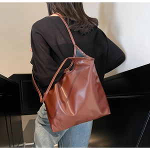 Detailed back view of a large brown leather tote bag worn by a model in a modern interior