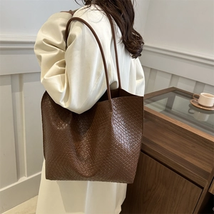 Brown woven leather tote bag shown on shoulder for a stylish casual commuter look