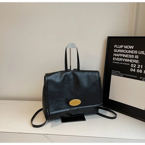 Close-up of black retro leather backpack featuring a stylish oval gold metal twist lock