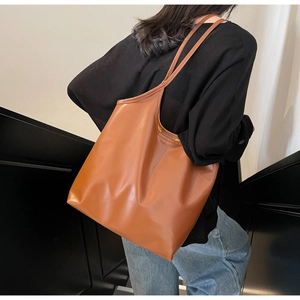 Detailed side view of the large brown tote bag being worn on a woman's shoulder