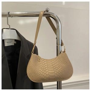 Detail shot of beige faux crocodile texture and gold hardware on the crescent bag