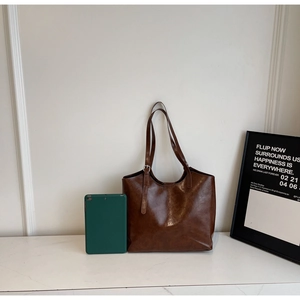 Detailed view of caramel brown oil wax leather tote with a tablet for size reference