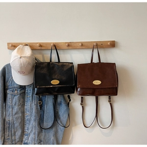 Detail of vintage oil wax leather backpacks in black and brown hanging on wooden hooks