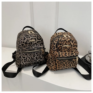 Close-up of leopard print mini backpacks in grey and brown with golden metal zippers