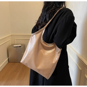 Close-up of minimalist apricot tote bag on model's shoulder showing smooth texture
