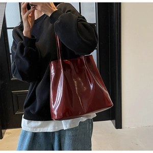 Detail of burgundy glossy patent leather tote bag showing shiny surface and slim strap