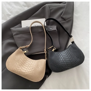 Detail of snake skin texture shoulder bags with gold hardware in beige and black colors