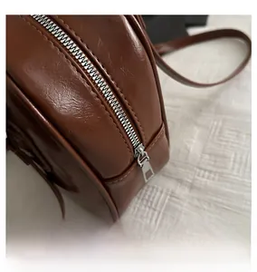 Close-up of smooth silver metal zipper on a premium brown synthetic leather handbag