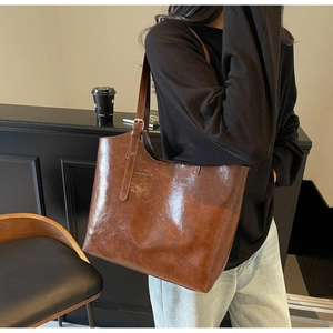 Detail of deep brown oil wax leather tote bag with adjustable strap on a model