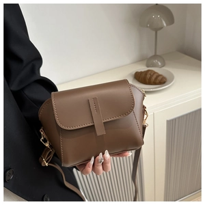 Détail d'un sac bandoulière en cuir marron foncé avec boucles dorées et rabat à sangle
