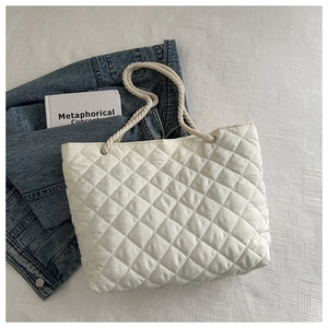Dettaglio borsa tote trapuntata in nylon bianco con manici in corda su sfondo denim