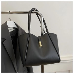 Detail der minimalistischen schwarzen Leder-Tote-Bag mit goldener Schließe am Bügel