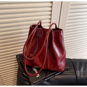 Macro view of high-gloss burgundy lacquer tote bag featuring minimalist slim straps