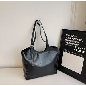 Close-up of black waxed leather tote bag with adjustable shoulder strap and silver hardware