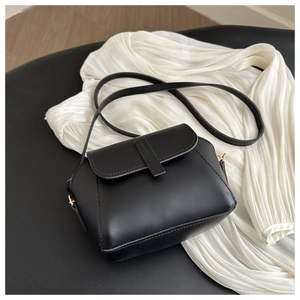Détail du sac bandoulière noir minimaliste en similicuir avec boucles en métal doré