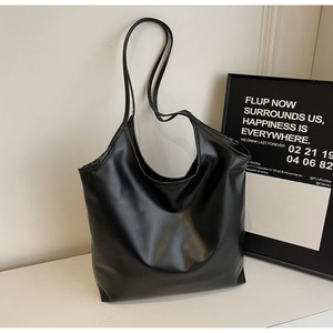 Detailed texture of a large black faux leather tote bag in a minimalist lifestyle setting