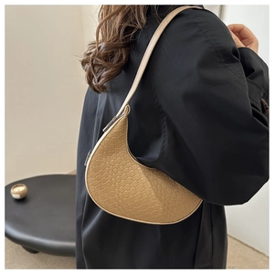 Détail de la texture tressée du sac demi-lune avec bandoulière sur manteau noir
