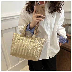Detail of metallic gold quilted handbag showing vertical stitching and glossy finish texture