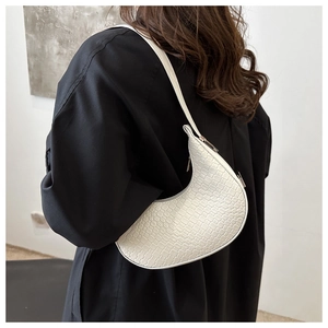Gros plan du sac en croissant blanc à motif crocodile sur un manteau noir élégant