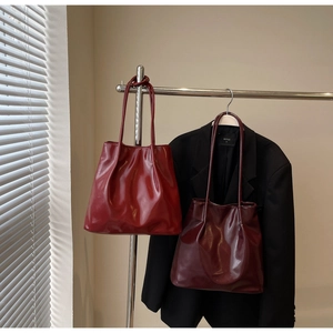 Detail of glossy patent leather tote bag featuring pleated texture and long shoulder straps