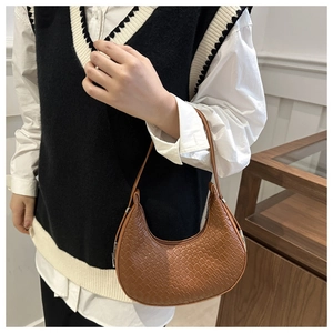 Vue détaillée de la texture tressée marron et de la forme demi-lune du sac hobo porté
