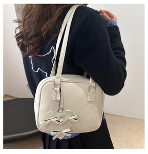 Detail of off-white leather square handbag with 3D bow heart charm and dual thin straps