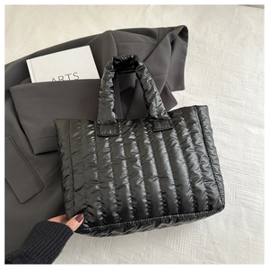 Detail of black quilted puffer tote bag with vertical stitching and soft nylon texture