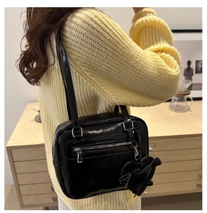 Glossy black patent leather shoulder bag with metallic zipper and heart-shaped bow charm