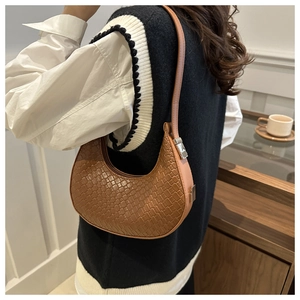 Gros plan du sac croissant tressé caramel montrant la texture du cuir entrelacé