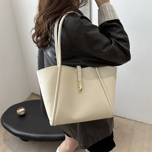 Minimalistische cremefarbene Leder-Tote-Bag mit goldener Schnalle an einem Model gezeigt
