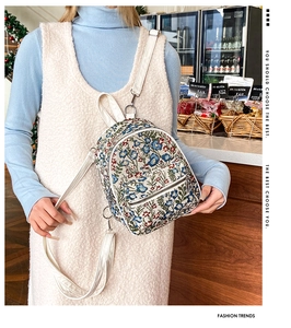Detail of floral tapestry backpack with white leather straps and silver zipper closure