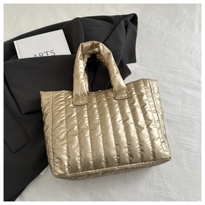 Detailed view of golden quilted tote bag with metallic finish on textured fabric