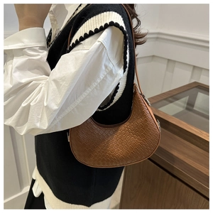 Détail d'un sac sous le bras en forme de lune marron avec texture gaufrée crocodile