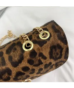 Détail du sac à bandoulière léopard en daim avec chaîne dorée et anneau métallique décoratif