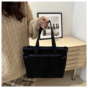 Detail of black corduroy tote bag showing multiple pockets and ribbed texture design