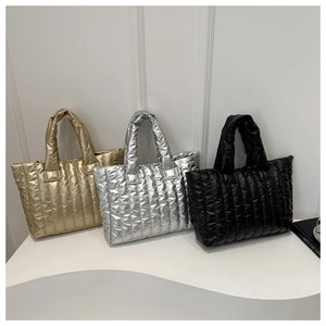 Three quilted down tote bags in gold, silver and black colors shown in a neat row