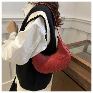 Gros plan du sac hobo rouge avec texture crocodile sur un pull en tricot noir