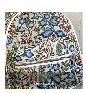 Close-up of floral jacquard fabric texture and silver metal zipper on the shoulder bag