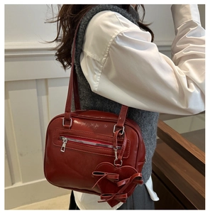Detail of dark red vintage faux leather shoulder bag with heart and bow charm