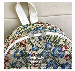 Detail of floral woven backpack featuring dual silver zippers and a white faux leather handle